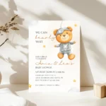 Neutral Tone: Astronaut teddy bear baby shower invitation card on a white table.